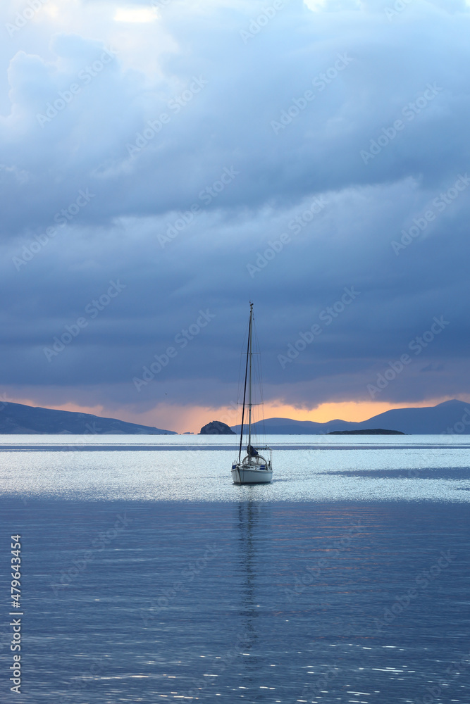 Alone sailboat at sunset. Atmospheric seascape with reflection 