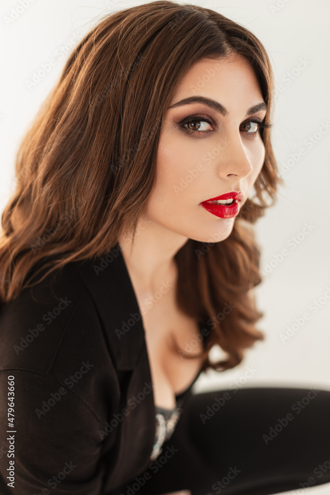 Fashion portrait of a beautiful young woman model with makeup and red lips in trendy black elegant clothes on a white background. Natural Beauty female face Fashion portrait of a beautiful young woman model with makeup and red lips in trendy black elegant clothes on a white background. Natural Beauty female face