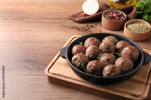 Tasty cooked meatballs served on wooden table. Space for text
