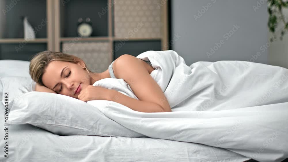 Beautiful female lying on comfortable bed covering by soft blanket enjoying night sleep recreation Beautiful female lying on comfortable bed covering by soft blanket enjoying night sleep recreation