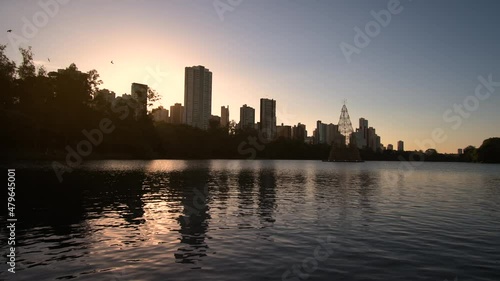 Panoramic view of a beautiful lake on golden hour sunset, few buildings and trees on the background. Landscape of Igapo lake, Londrina city, PR, Brazil.