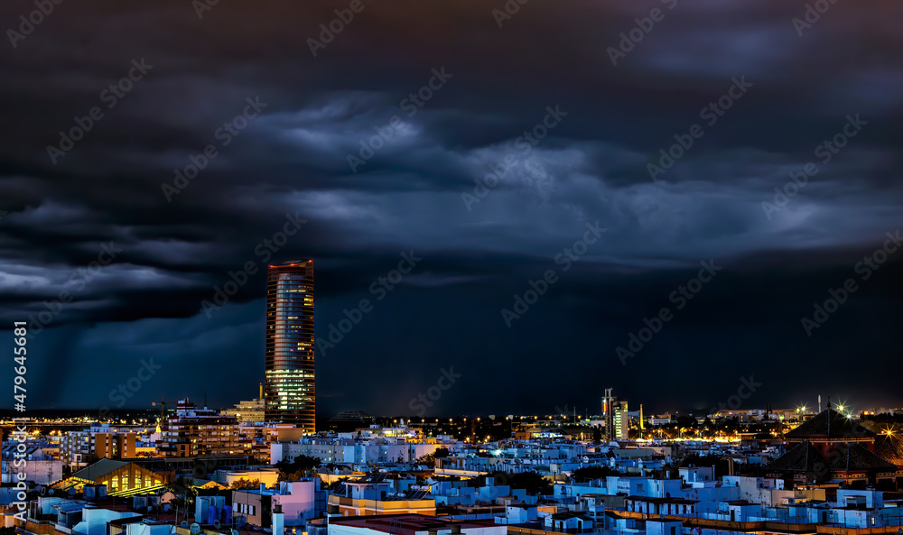 Fototapeta premium Spectacular view of Historic Triana Neighborhood and Seville city skyline a stormy night. Seville city, Tradition and Modernity