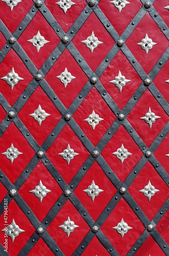 Medieval red door with diagonal iron stripes and silver stars photo