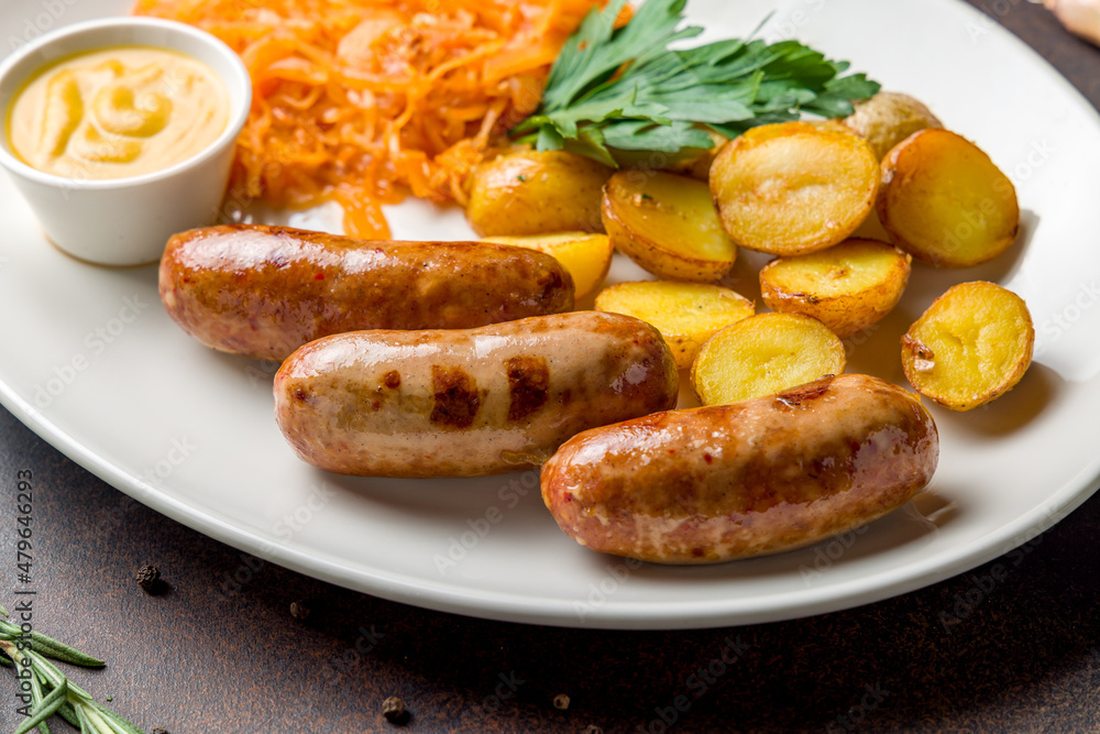 Fried hunter sausage with potatoes, fried cabbage and mustard on white plate on dark brown table macro close up Fried hunter sausage with potatoes, fried cabbage and mustard on white plate on dark brown table macro close up