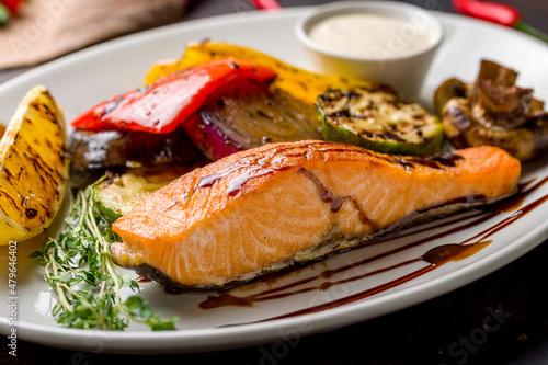 Salmon steak on the grill with grilled vegetables on plate macro close up