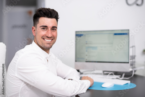 Happy handsome man working in office looking at camera