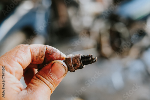 The motorcycle repairman is checking the spark plugs on the motorcycle engine.