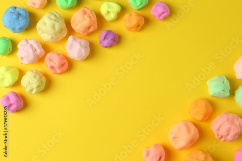 Different color play dough on yellow background, flat lay. Space for text