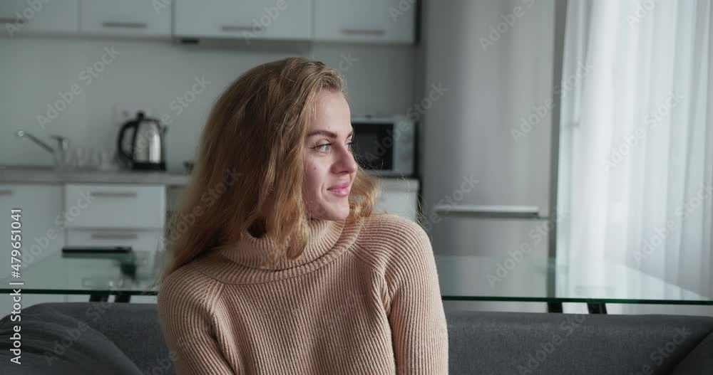 Pure happiness. Happy positive blonde curly woman in a warm sweater laughing at camera, sitting in couch at home, close-up portrait. Pure happiness. Happy positive blonde curly woman in a warm sweater laughing at camera, sitting in couch at home, close-up portrait.