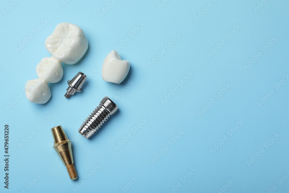 Parts of dental implant and bridge on light blue background, flat lay. Space for text - obrazy, fototapety, plakaty 