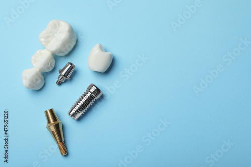 Parts of dental implant and bridge on light blue background, flat lay. Space for text photo