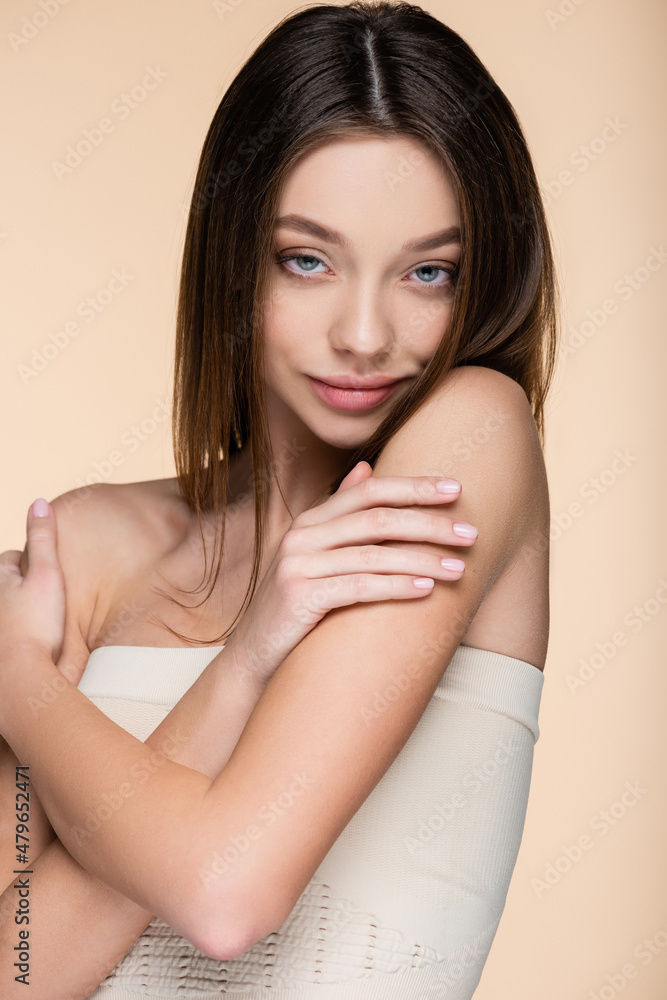 pretty woman in crop top touching bare shoulders isolated on beige pretty woman in crop top touching bare shoulders isolated on beige