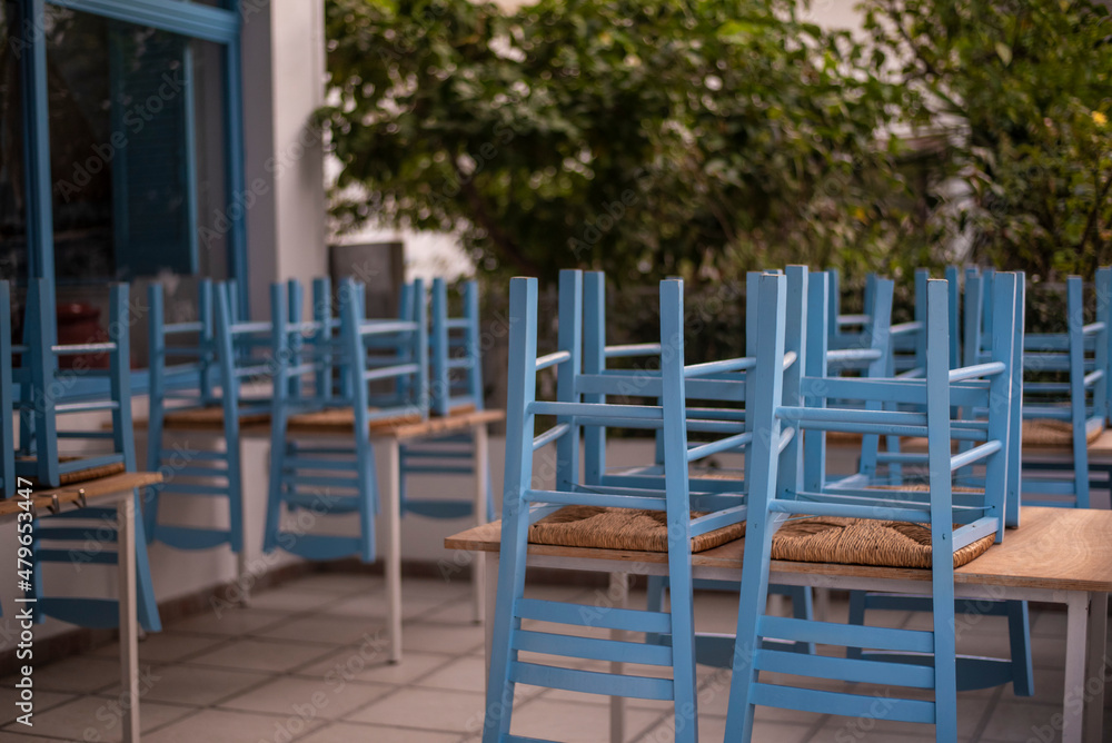 Blue chairs and tables stacked outside closed cafe-restaurant during the Coronavirus lockdown.