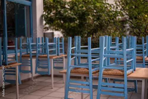 Blue chairs and tables stacked outside closed cafe-restaurant during the Coronavirus lockdown.