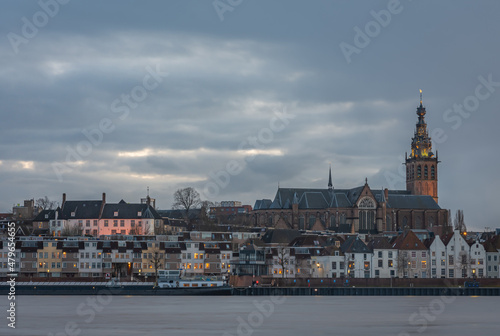 Skyline of dutch city Nijmegen at dusk with majestic Stephen s Church along the Waal river