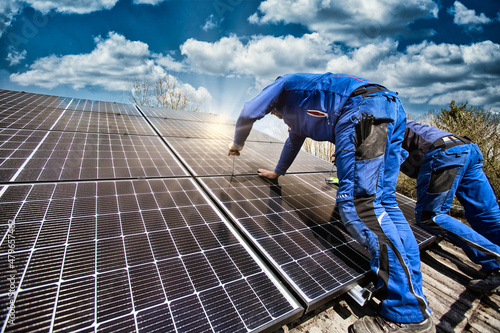 Installing solar photovoltaic panel system. Solar panel technician installing solar panels on roof. Alternative energy ecological concept.