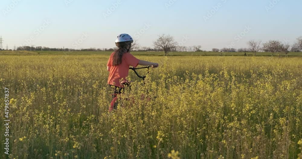 With bike in the flowers field. A view of little child stroll along the field in flowers during summer holiday. With bike in the flowers field. A view of little child stroll along the field in flowers during summer holiday.