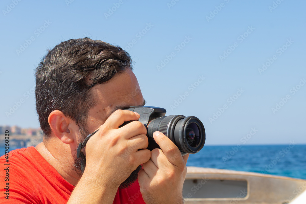 male photographer taking pictures with professional camera on summer next by the sea. Tourist taking photos of the beautiful landscape view on a ship riding