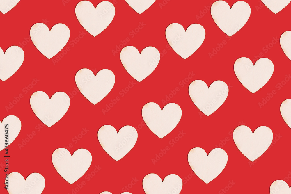 Wooden natural hearts as pattern on bright red background. Valentine holiday ready for romance. Minimal virtual love concept.
