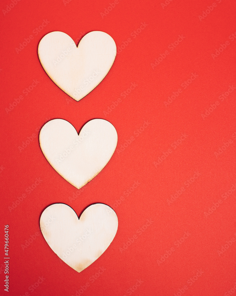 Tree wooden natural hearts on bright red background with copy space. Sharing valentine atmosphere. Minimal flat lay concept for holiday romance.