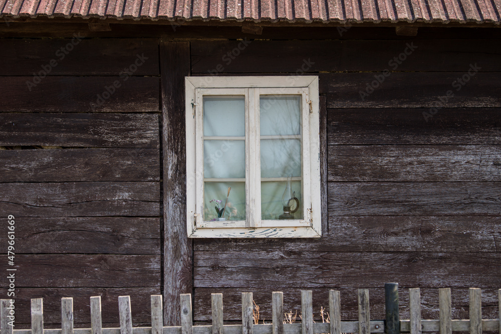 Sunja, Croatia, 05,04,2021: Rustic style aged window in wooden village rural home wall. Sunja, Croatia, 05,04,2021: Rustic style aged window in wooden village rural home wall.
