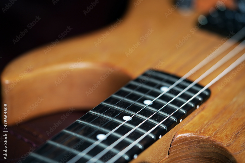 Fototapeta premium Guitar wallpaper. Musical instrument. Performance. Art. Strings. Electric guitar closeup detail. Music. Play. Wooden vintage guitar. Ukulele