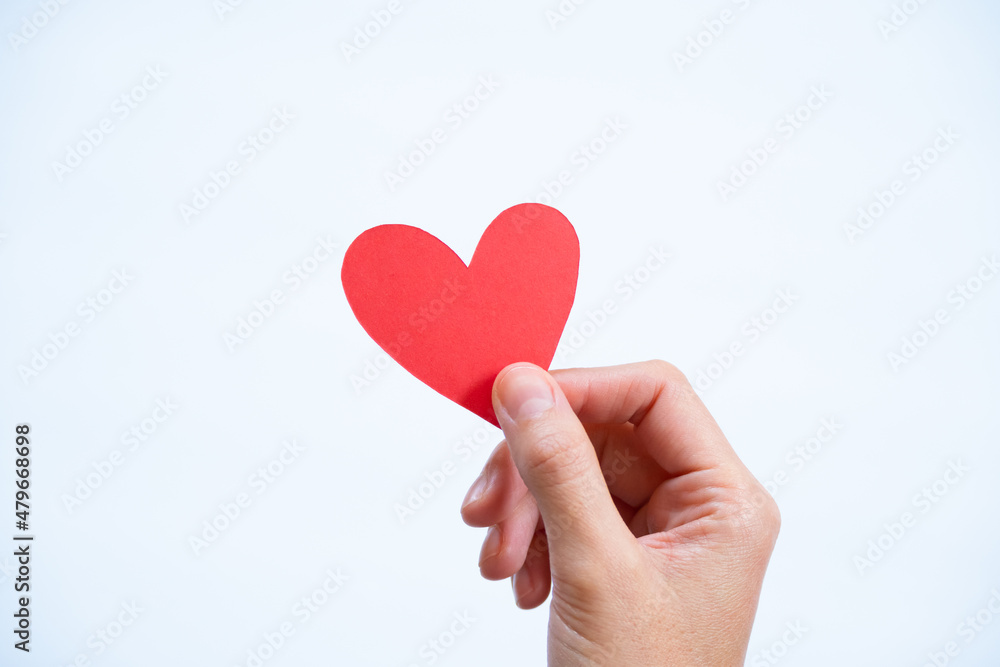 Hand holding paper heart on white background