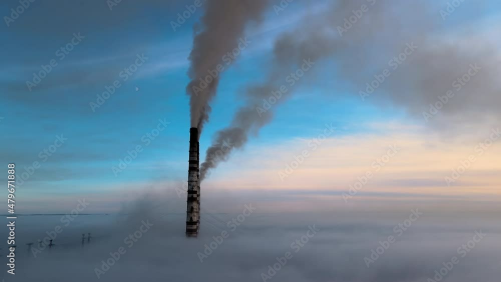 Aerial view of coal power plant high pipes with black smoke moving up polluting atmosphere at sunset