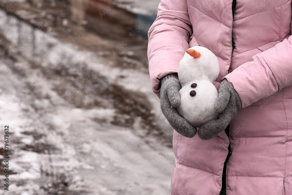 Snowman is melting in women's hands..Thaw warm winter or early spring. climate change as a result of global warming Snowman is melting in women's hands..Thaw warm winter or early spring. climate change as a result of global warming