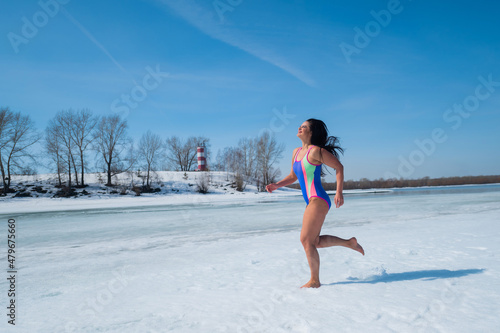 Caucasian woman in swimsuit runs barefoot in the snow. 