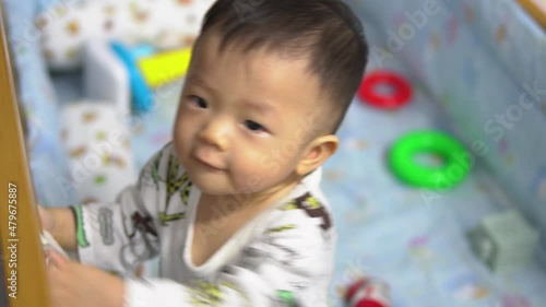 portrait footage of 10 month old Asian Chinese baby boy looks and move around surprisely on a bed photo