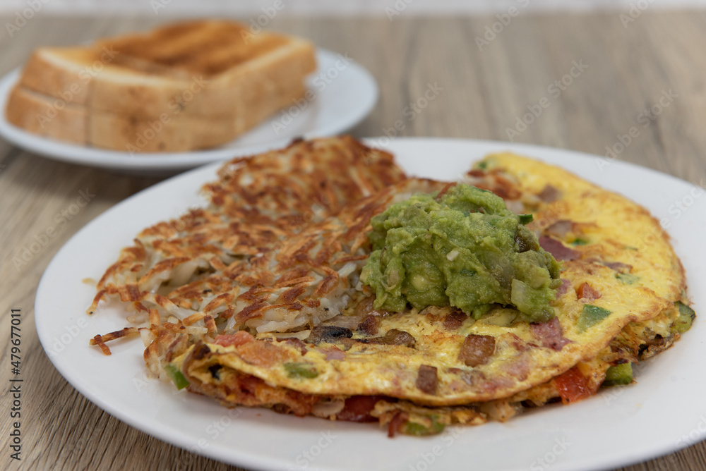 Eggs scrambled in a hearty omelette served with hash browns and toast for a tradional breakfast Eggs scrambled in a hearty omelette served with hash browns and toast for a tradional breakfast