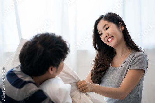 Young Asian couple happily playing with pillows on the bed together, Valentine's Day