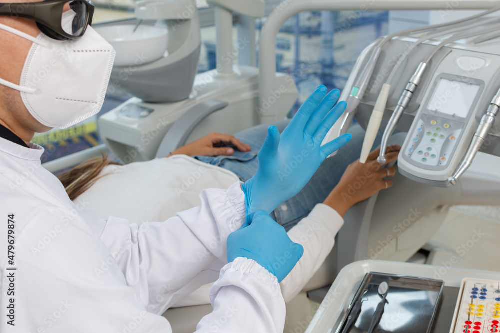 Close-up of dentist hands while putting on latex gloves to attend to a patient. Dental clinic concept