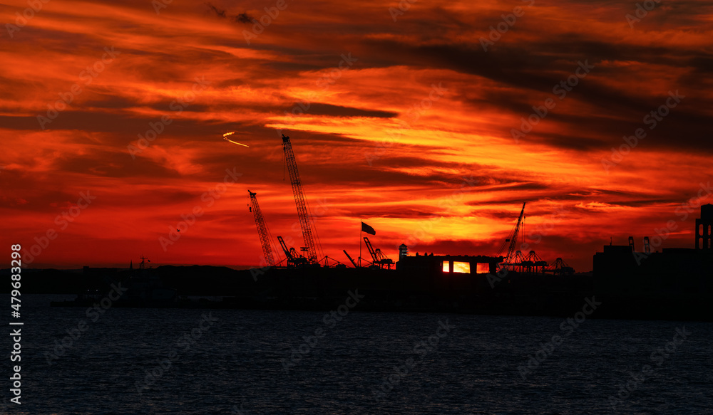 Jersey Port. Sunset view with crane silhouettes from the docking yard between Staten Island and Manhattan, New York. Cargo transportation and shipment industry.