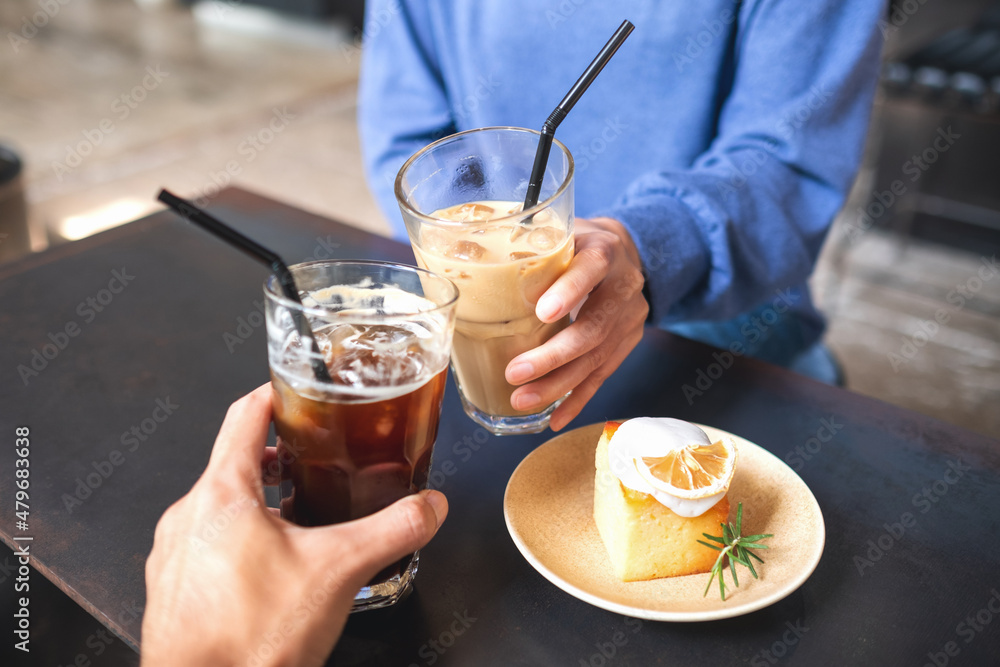 Closeup image of a couple people clinking coffee glasses together with lemon cake on the table in cafe Closeup image of a couple people clinking coffee glasses together with lemon cake on the table in cafe