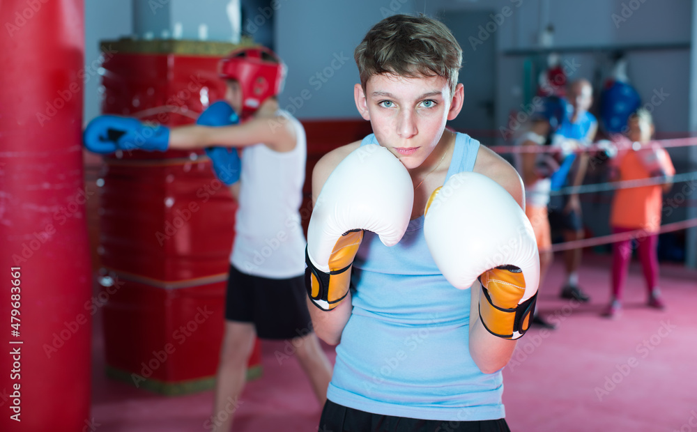 Serious teenager with boxing gloves posing in defended stance