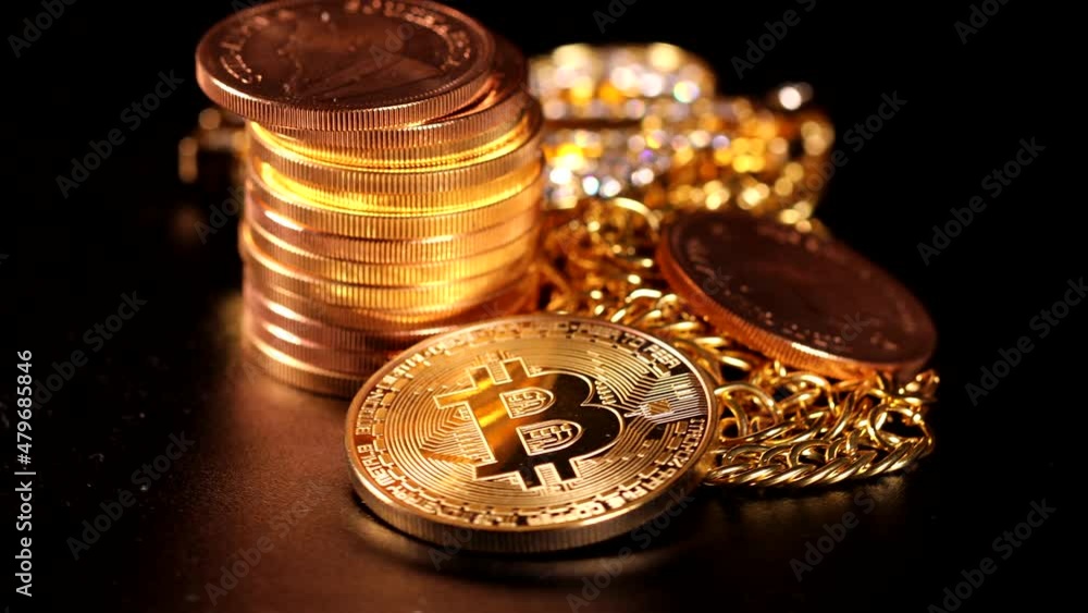 next to a pile of gold coins lies a bitcoin coin, a Krugerrand gold coin and a diamond studded gold chain