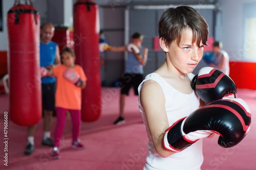Young serious teenager with boxing gloves posing in defended stance