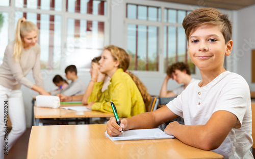 Portrait of positive schoolboy posing in classroom during lesson in secondary school