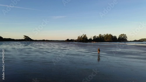 Female Photographer Walking Down An Empty Beach At Dawn photo