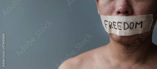 Man with mouth sealed in adhesive tape with Freedom message. Free of speech, freedom of press, Human rights, Protest dictatorship, democracy, liberty, equality and fraternity concepts photo