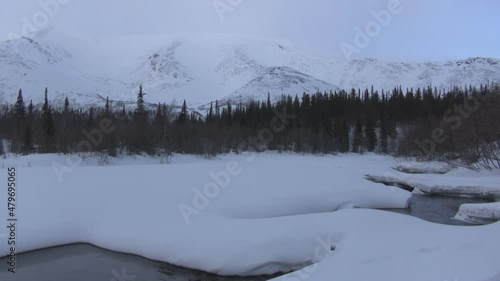 Winter weather in the far north, river, forest and mountains beyond the Arctic Circle, nature of the far north, snow on the banks of the river, winter mixed forest, trees in winter