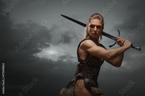 Foto Fantasy woman warrior in laether armor stained with blood and mud, holding sword