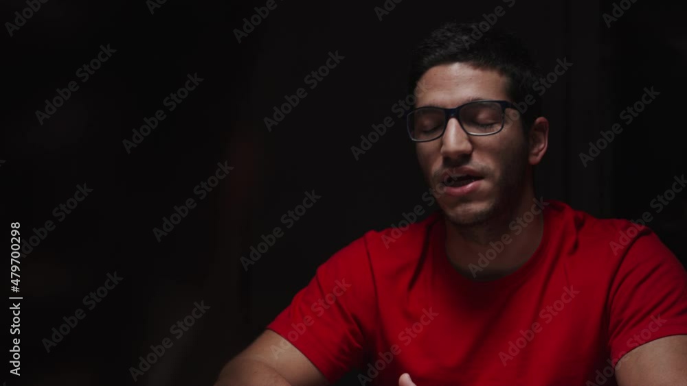 Medium closeup of young man talking to someone, noir lighting, interior, static Medium closeup of young man talking to someone, noir lighting, interior, static