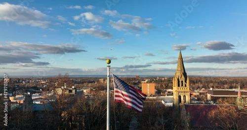 Static aerial of American USA flag during dramatic sunset. Airplane flies in distance. Golden hour light on church steeple in small town USA. photo