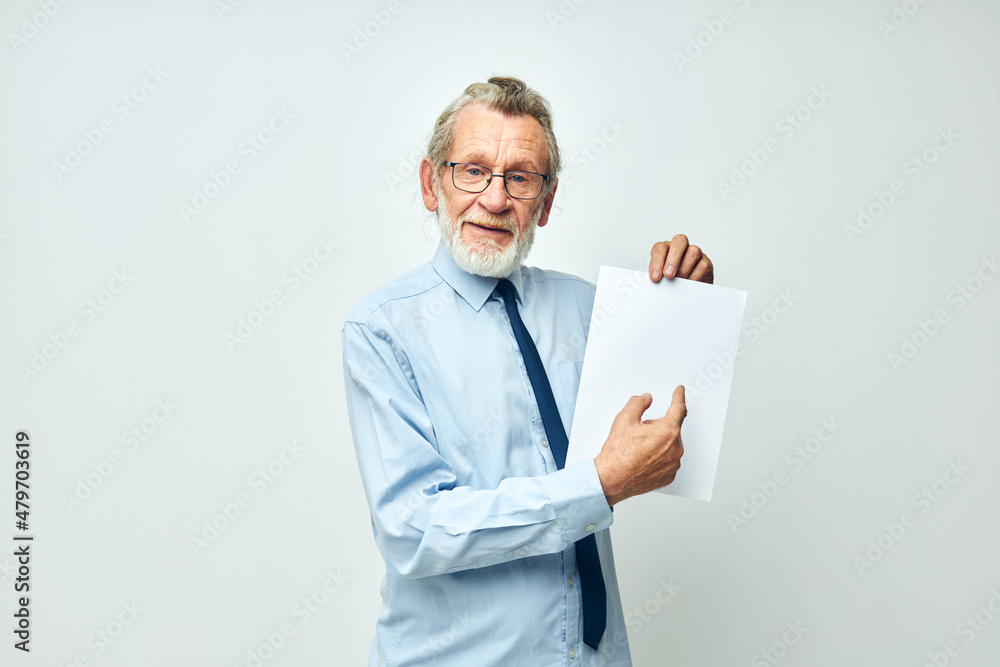 Senior grey-haired man holding documents with a sheet of paper light background Senior grey-haired man holding documents with a sheet of paper light background