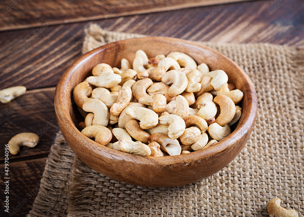 Tasty cashew nuts in bowl on wooden table. Tasty cashew nuts in bowl on wooden table.