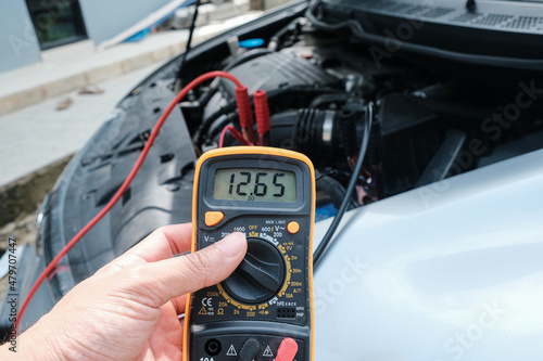 Mechanic man hand checking voltage of car battery maintenant photo