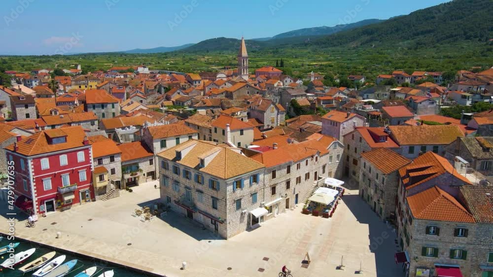 Panorama of a coastal town with many houses with red roofs, surrounded by the sea and mountains with yachts in marina bay and Bell tower and people on bike Panorama of a coastal town with many houses with red roofs, surrounded by the sea and mountains with yachts in marina bay and Bell tower and people on bike